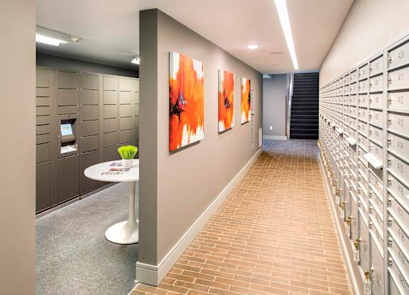 A hallway with a table and chairs and a row of mailboxes on the right.