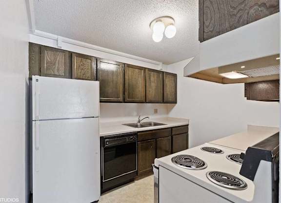 A kitchen with a white refrigerator, a white stove, and wooden cabinets.