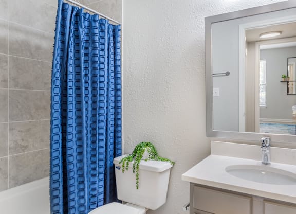 A white toilet with a blue curtain in the shower.