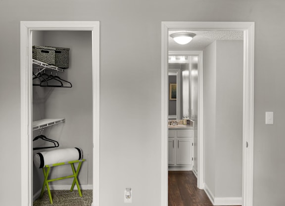 A white closet with a mirror and a chair.