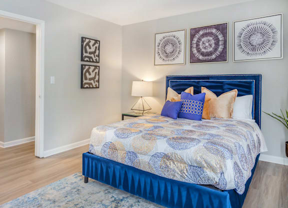 A bedroom with a blue bed and a white wall.