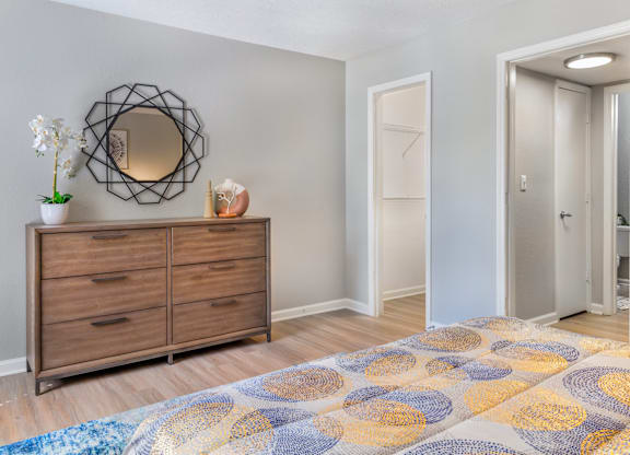 A room with a wooden dresser and a round mirror on the wall.
