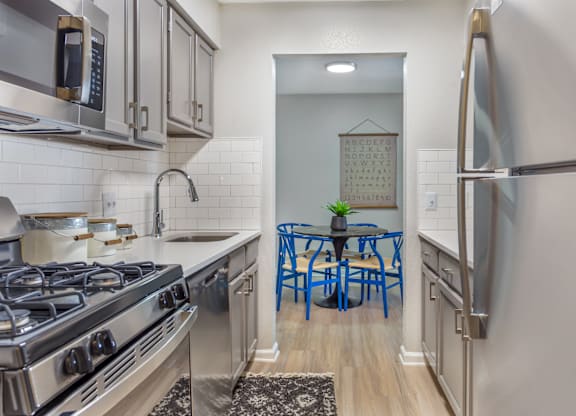 A kitchen with a stove, refrigerator, and blue chairs.