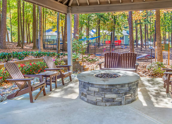 A patio with a fire pit and chairs.