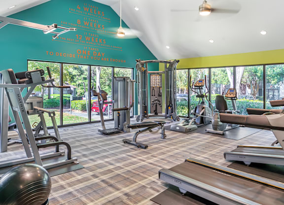 A gym with a variety of equipment including treadmills, weights, and exercise machines.