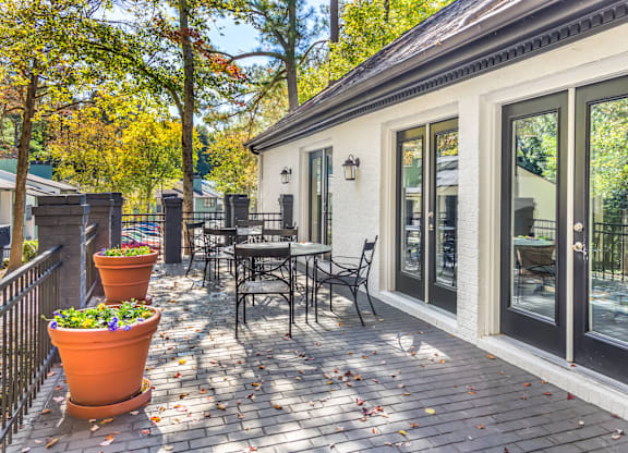 A patio with a table and chairs is surrounded by trees.
