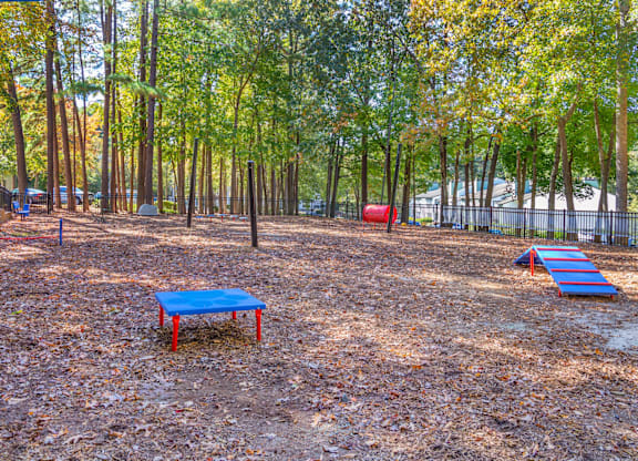 A playground with a blue slide and red and blue swings.