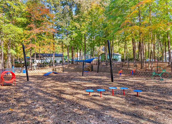 A playground with a red swing set and blue and red slides.