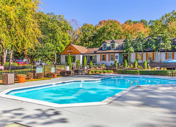 A large swimming pool in front of a house surrounded by trees.
