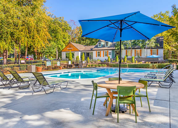 A blue umbrella is over a table with chairs around it.