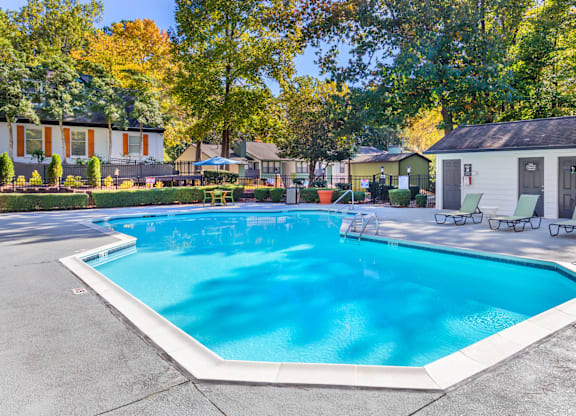 A large swimming pool surrounded by trees and houses.