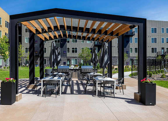 A patio with a table and chairs under a wooden pergola.