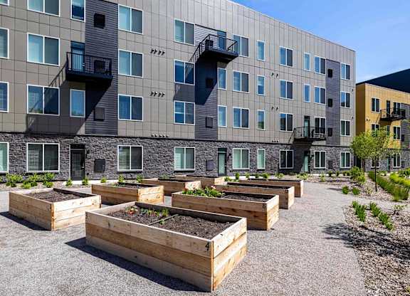 A building with grey and yellow panels and balconies with wooden planters in front.