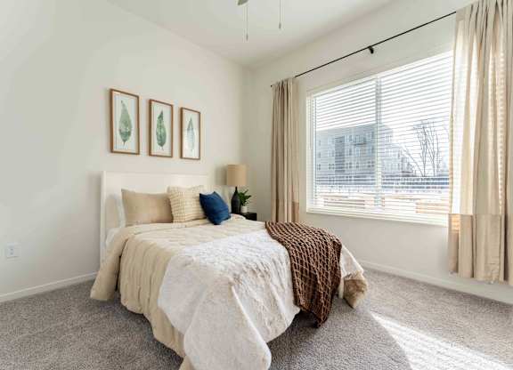 A bedroom with a bed, pillows, and pictures on the wall.
