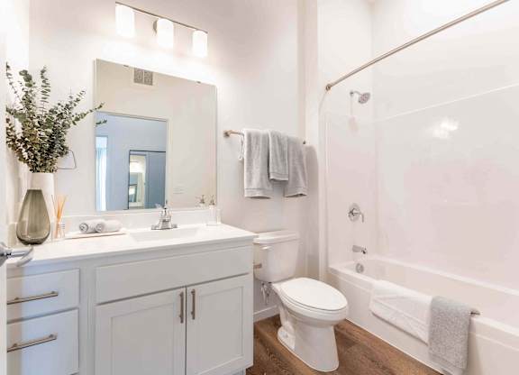 A white bathroom with a toilet, sink, and mirror.