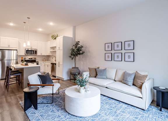 A modern living room with a white couch and a blue patterned rug.