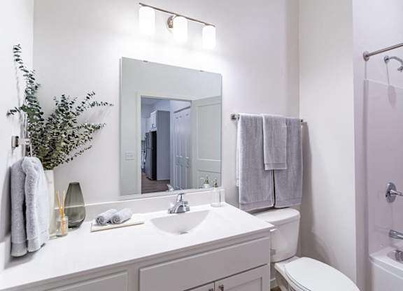 A white bathroom with a white sink and toilet.