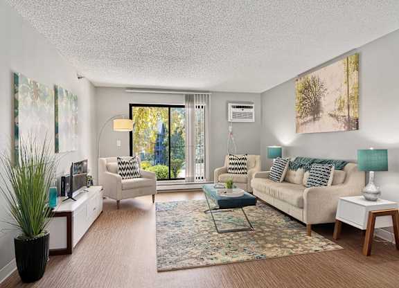 A living room with a couch, chair, and potted plant.