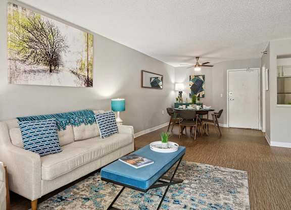 A living room with a white couch, a blue coffee table, and a painting on the wall.