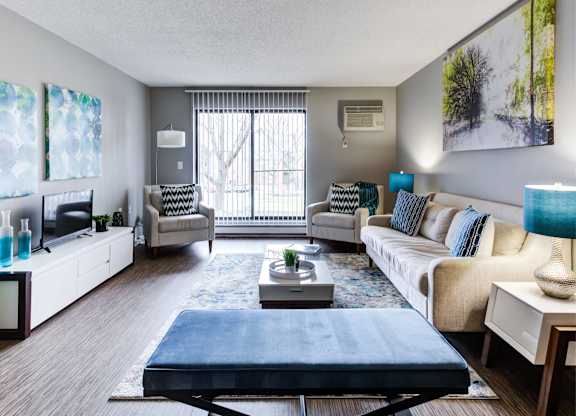 A living room with a blue ottoman in the center.