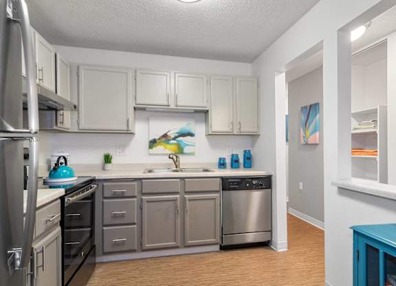 A kitchen with a refrigerator, oven, and sink.