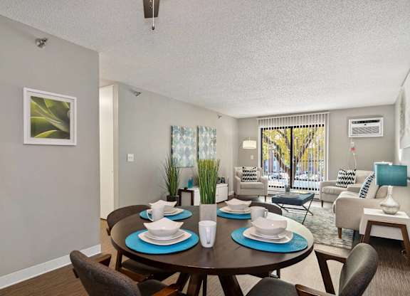 A dining room with a table set for two and a couch with a blue cushion.
