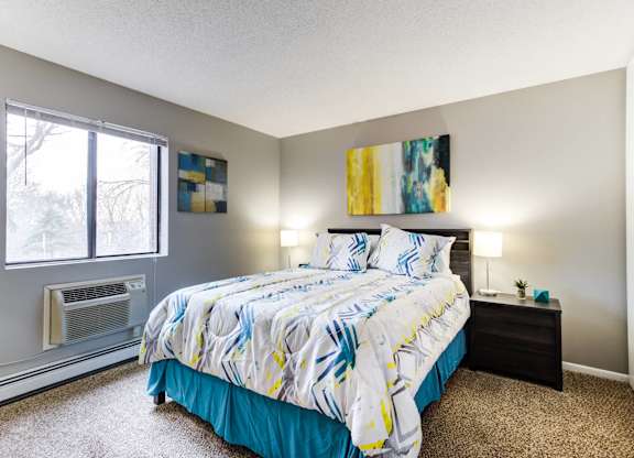 A bedroom with a bed, nightstand, and window.
