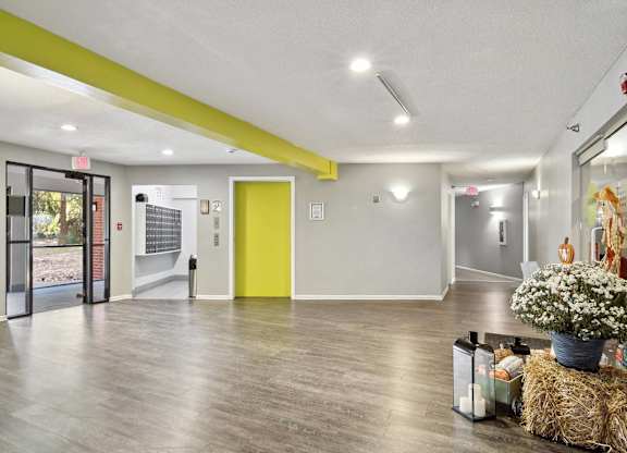 A brightly lit hallway with a yellow door and a grey door.