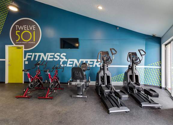 A fitness center with a row of treadmills and stationary bikes.