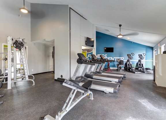 A gym with a variety of equipment including treadmills, weights, and exercise machines.