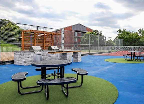 A playground with a blue surface and a picnic table.