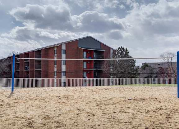 A red brick building with a sandy area in front.