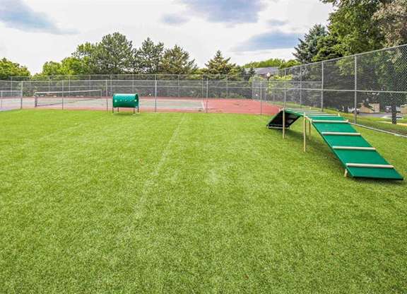 A green grassy field with a fence and benches.
