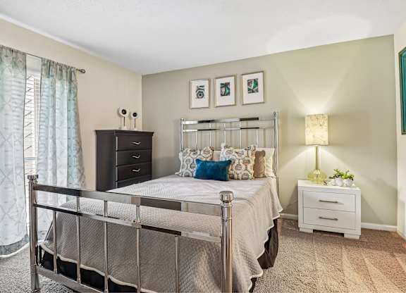 A bedroom with a bed, nightstand, and lamp.