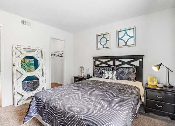 A bedroom with a bed, nightstand, and lamp.