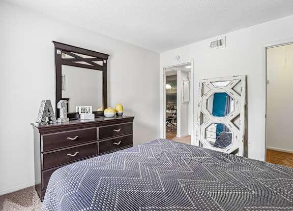 A bedroom with a large bed and a dresser with a mirror above it.