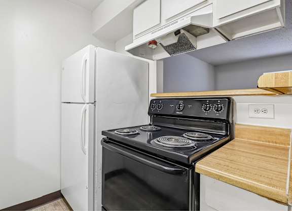 A black stove in a kitchen with a white fridge.