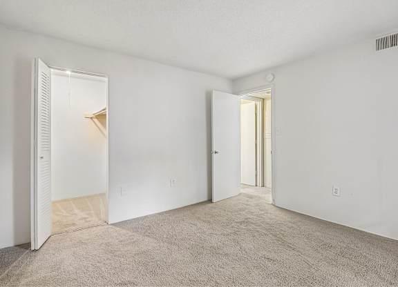 A room with carpeted floor and two open doors.