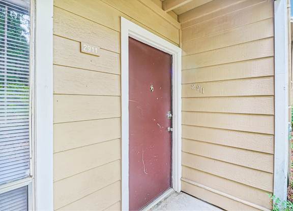 A red door with a white frame is on the side of a house.