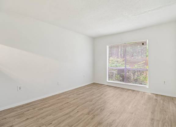 Empty room with wooden flooring and a window.