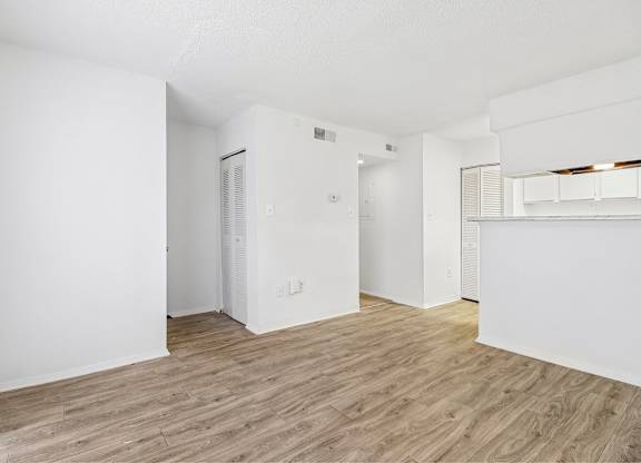 A spacious room with wooden flooring and white walls.