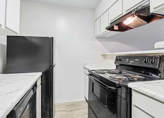 A black refrigerator is on the left and a black oven is on the right in a kitchen.