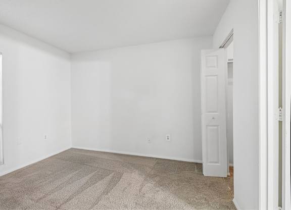A room with a carpeted floor and a white door.