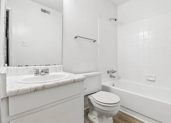 A white bathroom with a marble sink and toilet.