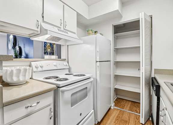 A white kitchen with a stove, oven, and refrigerator.