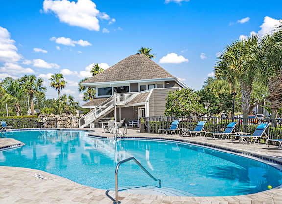 A swimming pool with a slide and a house in the background.