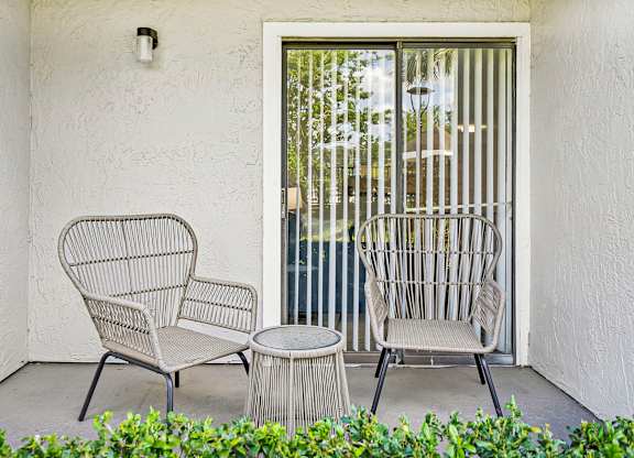 Two chairs and a table are on a patio.