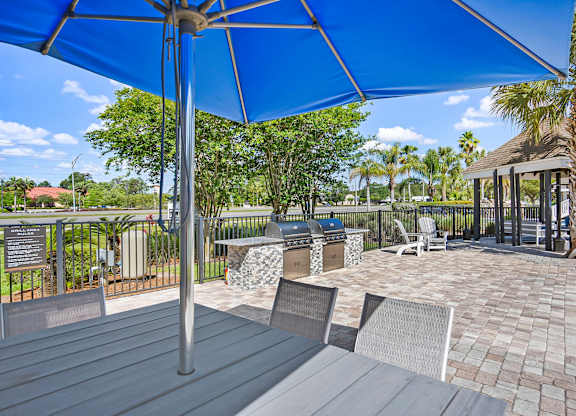 A patio with a blue umbrella and chairs.