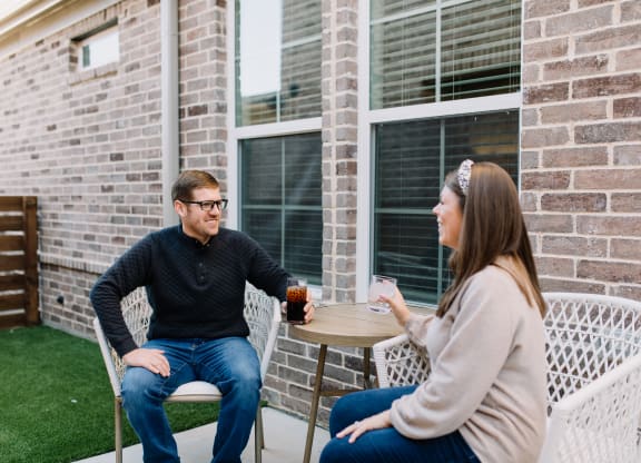 a man and a woman sitting at a table on a patio