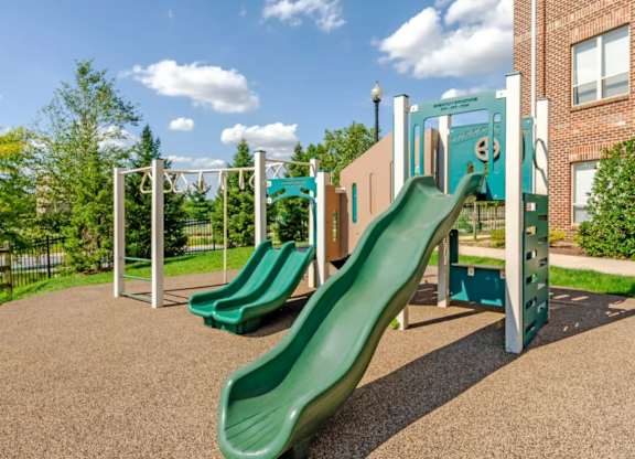 A playground with a green slide and a climbing frame.